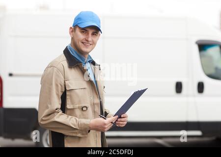 Portrait of young man smiling at camera while standing outdoors he working in delivery company Stock Photo