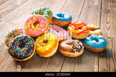 Various colorful donuts on wooden background Stock Photo