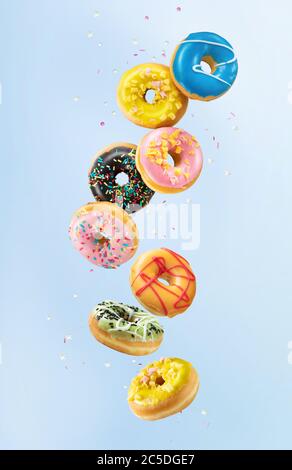 Various colorful doughnuts falling or flying in motion on blue background Stock Photo