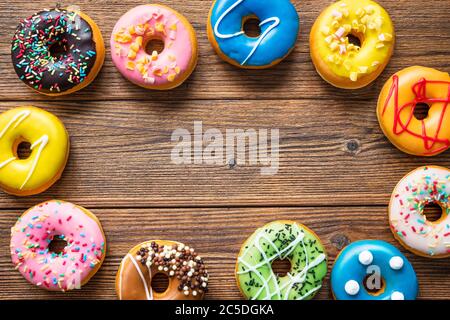 Various colorful donuts on wooden background Stock Photo