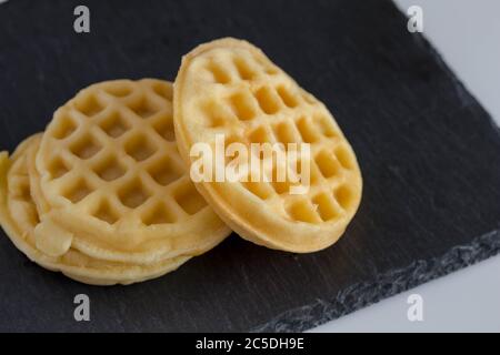 Round small waffles on black slate background waffles with copy space - selective focus Stock Photo