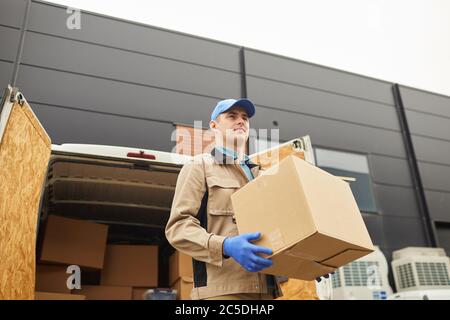 Young man in uniform carrying boxes outdoors he unloading the van Stock Photo