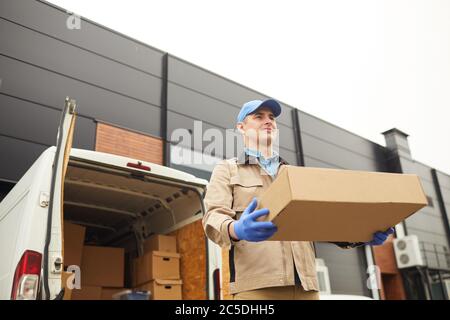 Young man in uniform carrying big cardboard box he working in cargo delivery Stock Photo