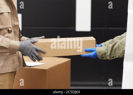 Close-up of manual workers in gloves passing the box to each other they working with loads in warehouse Stock Photo