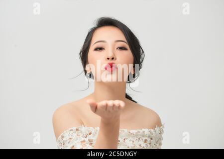 Asian bride with duck face sending air kiss isolated on white Stock Photo