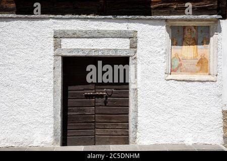 An old wooden door and a religius paint at Canza village, Formazza Valley, Ossola Valley, VCO, Piedmont, Italy Stock Photo