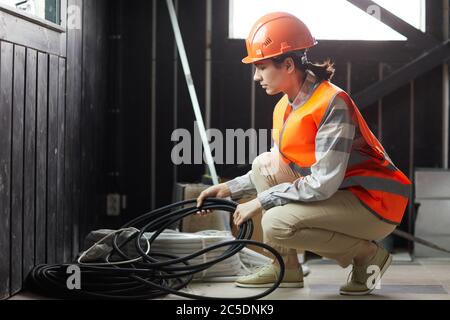 Young woman in work helmet taking wires she working in construction site Stock Photo