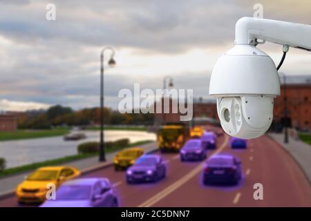 The concept of video surveillance and security technology. CCTV camera on the background of a road bridge with traffic in cloudy weather. Stock Photo