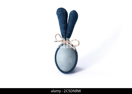 Easter egg with blue denim bunny ears on white background. DIY idea. Minimal happy Easter concept. Closeup. Copy space Stock Photo
