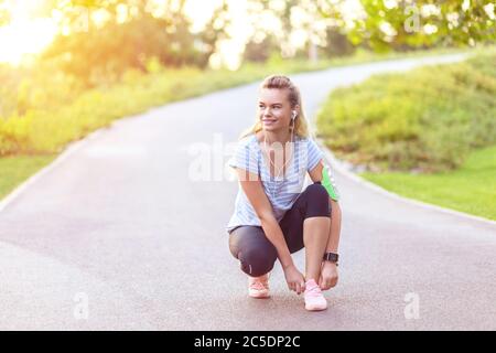 Young fitness woman tie shoelace of sport shoes on city running track Stock Photo