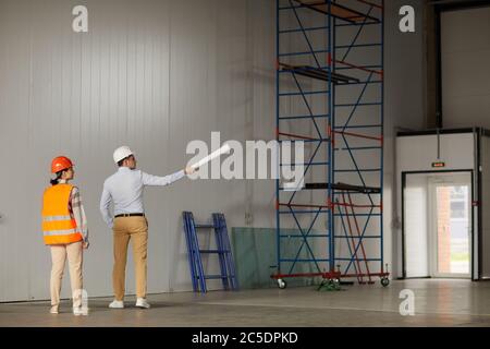 Two engineers standing in empty building and discussing the new construction project Stock Photo