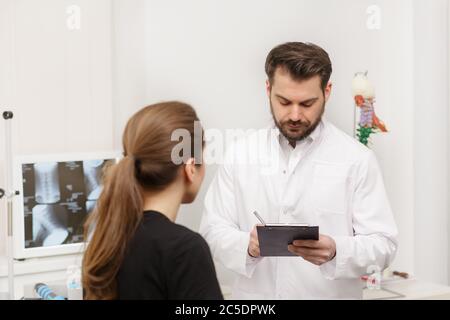 Doctor and patient in medical office. Therapist talking to patient in office, taking notes, writing prescription. Consultation in clinic. Healthcare Stock Photo