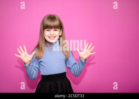 Portrait of funny girl showing ten fingers isolated on pink background Stock Photo