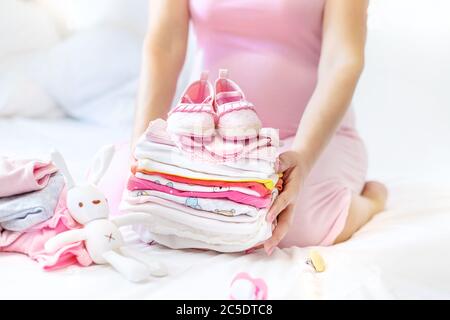 A pregnant woman is folding baby things. Selective focus. people. Stock Photo