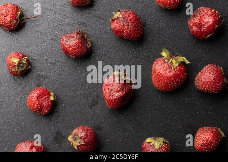 the spoiled strawberry berry is beautifully laid out on a textured stone surface. Stock Photo