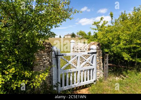 A glimpse of a classical country house built since 2012 on the Farmcote Estate viewed from Campden Lane on the Cotswold Hills, Gloucestershire UK. Stock Photo