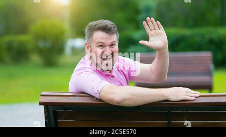 Happy adult man with gray hair waves his hand. Stock Photo