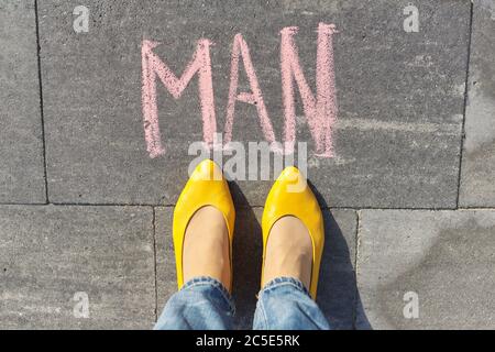 Man concept, top view on woman legs and text written in chalk on gray sidewalk Stock Photo