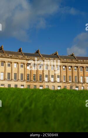 Low angle view of the Royal Crescent in Bath, Somerset with lush green lawn in the foreground and blue summer sky in the background. Stock Photo