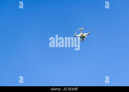 Drone quad copter with onboard high resolution digital camera flying in the blue sky Stock Photo