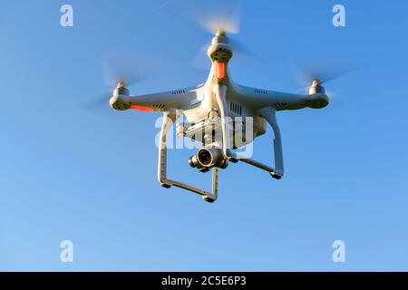 Drone quad copter with onboard high resolution digital camera flying in the blue sky Stock Photo