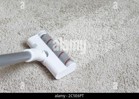 Vacuum cleaner head on dirty carpet with clean strip. Housework with using hoover. Turbo brush of modern vacuum cleaner close up. Home cleaning and ca Stock Photo