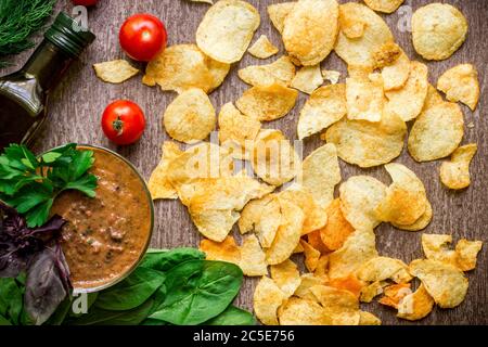 Potato chips with dipping sauce on a wooden table. Unhealthy food on a wooden background. Stock Photo