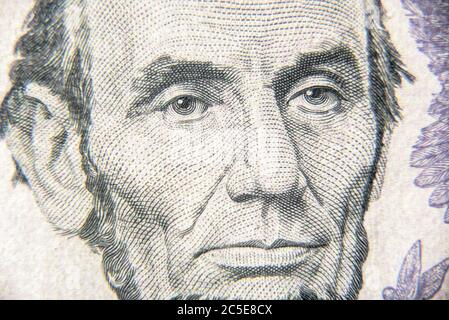 Abraham Abe Lincoln face on 5 dollar bill close up. Portrait of famous US president on dollar banknote. Macro view of USA paper money. Detail of new c Stock Photo