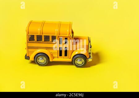 Simply design yellow classic toy car school bus isolated on yellow colorful background. Safety daily transport for kids. Back to school concept. Education symbol. Copy space Stock Photo