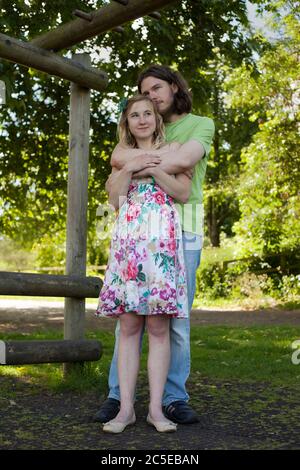 Embracing young lovers in park on a sunny summer day, Springfield Park, London, model release available Stock Photo