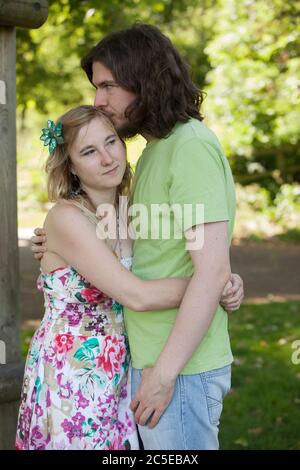 Embracing young couple in park on a sunny summer day, Springfield Park, London, model release available Stock Photo