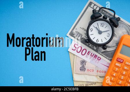 MORATORIUM PLAN text with alarm clock, banknotes currencies and calculator on blue background. Coronavirus Covid19 and Business Concept Stock Photo