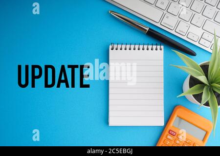 UPDATE text with fountain pen, notepad, decorative plant and keyboard on blue background. Coronavirus Covid19 and Business Concept Stock Photo