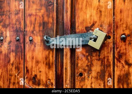A sturdy, old-fashioned but efficient padlocked bolt closes a wooden door in Cuenca in Ecuador Stock Photo