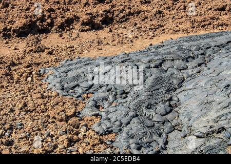 The flow of smooth and billowy black basaltic lava contrasts with the red of the oldest rocks of Santiago Island, Galapagos Stock Photo