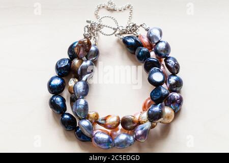 handcrafted bracelet from colored natural river pearls and silver clasp close up on pale wooden board Stock Photo