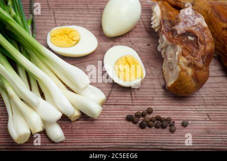 Boiled eggs, fresh chives and smoked chicken laid out on a board Stock Photo