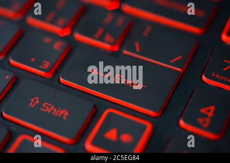 Red backlit computer keyboard macro shot of enter key Stock Photo