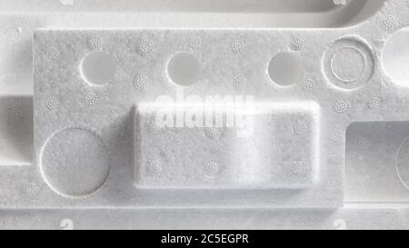 Polystyrene or styrofoam padding for product packaging. Detail of styrene foam plastic box close-up. White styrofoam cushion texture background. Stock Photo
