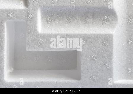 Polystyrene or styrofoam padding for product packaging. Detail of styrene foam plastic box close-up. White styrofoam cushion texture background. Stock Photo