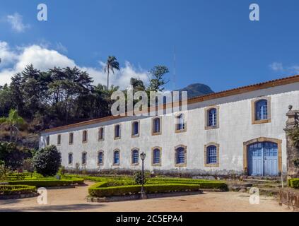 Old two-story building, from the colonial period, with beautiful garden in front and forest in the background, blue sky, Caraca Sanctuary, city of Cat Stock Photo