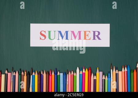 Summer vacation concept. Top above overhead view photo of summer paper and colorful crayons isolated on greenboard Stock Photo