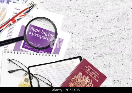 English violet guide Applying for a passport lies on table with office items. UK passport paperwork process Stock Photo