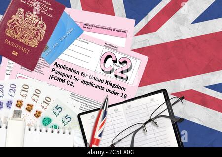English form C2 Application for United Kingdom passport for applicants under 16 lies on table with office items. UK passport paperwork process Stock Photo