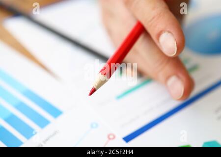 Fingers hold red pencil on background diagrams Stock Photo