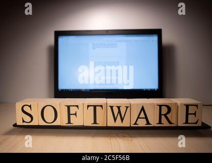 The laptop screen on the table is open. Software word on wooden cubes on laptop. Stock Photo