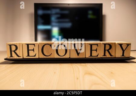 Recovery word from wooden cubes on laptop. Stock Photo
