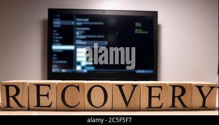 Recovery word from wooden cubes on laptop. Stock Photo