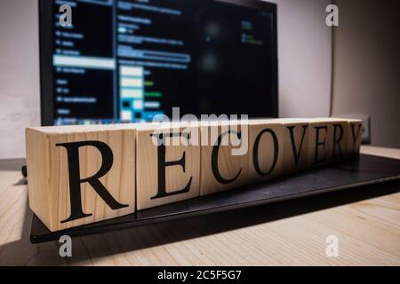 Recovery word from wooden cubes on laptop. Stock Photo