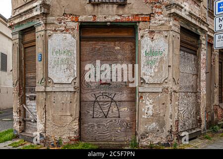 The slogan "Danke Merkel – wir schaffen das!" ("thank you, Merkel – we can do this") is sprayed in green on a boarded wooden door on a derelict corner building in Görlitz, Saxony, above a circled "M" symbol. Right-wing extremists intended the phrase as an ironic attack on then chancellor Angela Merkel. Weathered plaster and exposed brickwork frame the doorway. Stock Photo